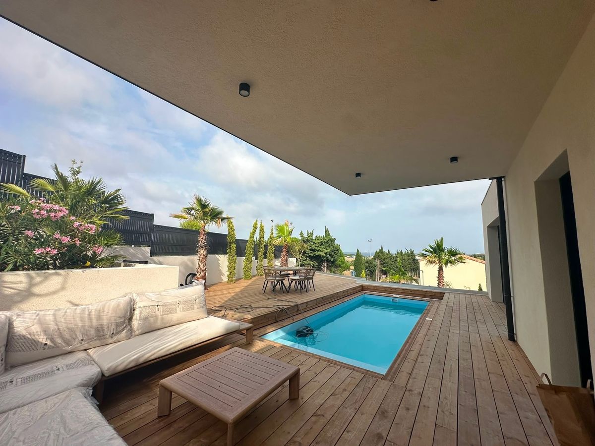 Terrasse couverte sous le porte-à-faux de la villa container, vue dégagée sur la plaine et la Méditerranée